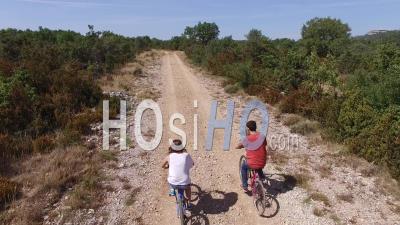 Two Cyclists Riding On A Rural Track In The Garrigue Or Scrubland In The South Of France – View From Above By Drone