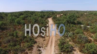 Two Cyclists Riding On A Rural Track In The Garrigue Or Scrubland In The South Of France – View From Above By Drone