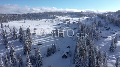 Flying Over Mountain Homestead With Small Huts Covered By Snow - Video Drone Footage