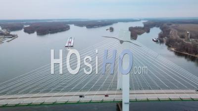 Aerial View Of A Coal Barge Pushed By Tugboat Moving Up The Mississippi River Near Burlington Iowa With Suspension Bridge Foreground - Video Drone Footage
