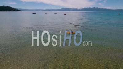 An Aerial View Of A Woman Paddling A Kayak Across Lake Tahoe - Video Drone Footage