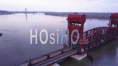 Aerial View Of A Coal Freight Train Crossing A Long Suspension Bridge Over The Mississippi River - Video Drone Footage