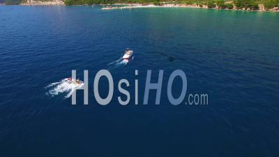 Aerial View Of Adventure Boat Towing Four Innertubes For A Tubing Adventure Off The Coast Of Croatia - Video Drone Footage
