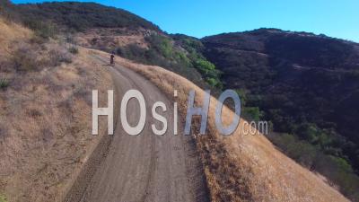 Aerial View Of A Mountain Biker Riding Fast Down A Mountain - Video Drone Footage