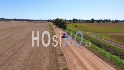 A Red Pickup Truck Traveling On A Dirt Road In A Rural Farm Area Of Mississippi - Aerial Video By Drone