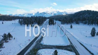 2020 - Vidéo Aérienne De Voitures Roulant Lentement Sur Une Route De Montagne Couverte De Neige Glacée Dans Les Montagnes De L'est De La Sierra Nevada Près De Mammoth En Californie - Vidéo Par Drone