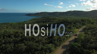 Aerial View Of A Car Driving Through Lush Green Landscape - Video Drone Footage 