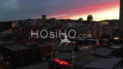 Moody Aerial Around Portland Oregon Stag Deer Sign And Downtown Old Town Cityscape And Business District At Sunset Or Dusk. - Video Drone Footage