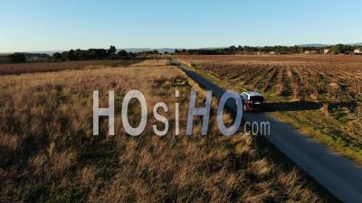 Car Driving On A Countryside Road In A Grazing Light, Video Drone Footage
