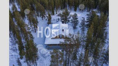 Aerial Drone Photo Of Wooden Cabin In The Remote Forest, With Snow Covered Woods And Trees Landscape In Lapland, Finland