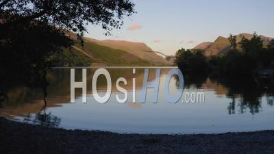 Beau Paysage Dans Le Lac Llyn Padarn Avec Des Reflets De L'eau Des Arbres Et Des Montagnes Contre Le Ciel Bleu D'été Dans Le Parc National De Snowdonia à Llanberis, Au Nord Du Pays De Galles - Drone Vidéo