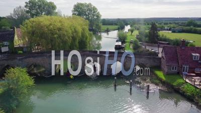 Group Of People Paddling Kayak Under A Bridge In River Thames In Abingdon Town Near Oxford City, Uk. - Aerial Drone Shot