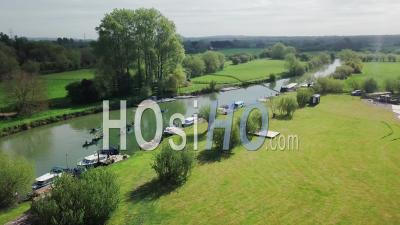 Boats Moored On The Edge Of River Thames With People Kayaking On The Water In Abingdon Near Oxford City, Uk.- Aerial Drone Shot