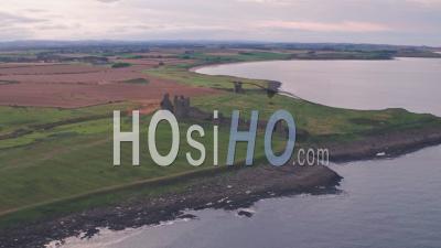 Ruins Of Dunstanburgh Castle At Sunset, Northumberland, England, Uk. Aerial Drone View