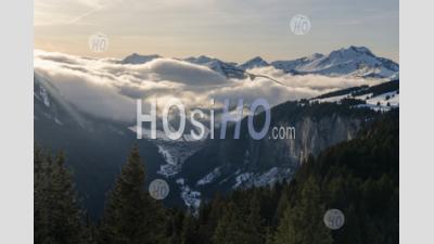 Dramatic Snowy Winter Mountain Landscape With Low Misty Clouds And Forests At The Ski Resort Of Morzine, Alps, France, Europe