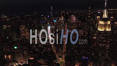 Vue Panoramique à Couper Le Souffle Sur L'emblématique Empire State Building Disparaissant Derrière Des Immeubles Résidentiels Et Des Immeubles De Bureaux à Midtown Manhattan, New York City La Nuit 4k - Drone Vidéo