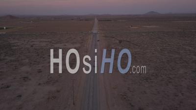 Flight Over Lonely Abandoned Desert Road With Red Car Driving In The Distance 4k - Video Drone Footage