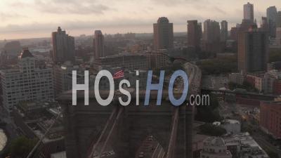 Close Up Flight Over Brooklyn Bridge With American Flag And Foggy New York City Skyline In Beautiful 4k - Video Drone Footage