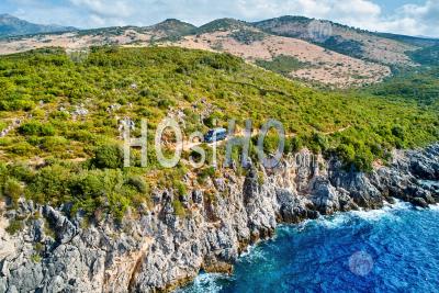 Off Road Campervan Driving On Dangerous Sandy Road On The Edge Of Rocky Cliff Above Blue Sea - Aerial Photography