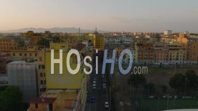 Fly Above Street In City. Colour Apartment Houses Lit By Rising Sun. Various Houses In Urban Borough. Rome, Italy - Video Drone Footage