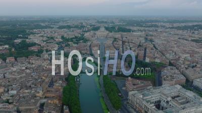 Backwards Fly High Above Tiber River In City. Historic Buildings And Large Palaces At Twilight. St. Peters Square With Large Basilica In Vatican City In Background. Rome, Italy - Video Drone Footage