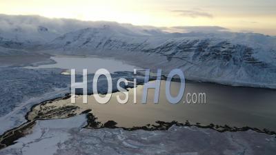 An Aerial View Shows Snow-Covered Mountains Circling A Lake In Iceland - Video Drone Footage
