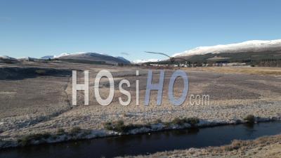Dalwhinnie Distillery And Dalwhinnie Town With Ben Alder In The Background - Video Drone Footage