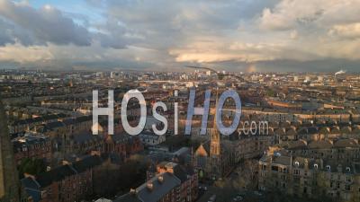Church Steeples With A Rainbow During A Spring Afternoon With Tenement Housing, The City Centre And The Campsies Mountains In The Background - Video Drone Footage