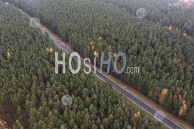 Aerial View Of Countryside Road Passing Through The Autumn Forest. Captured From Above With A Drone.