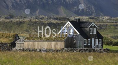 Maison Solitaire En Bois Noir Au Pied De La Montagne, En Islande.