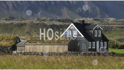 Maison Solitaire En Bois Noir Au Pied De La Montagne, En Islande.